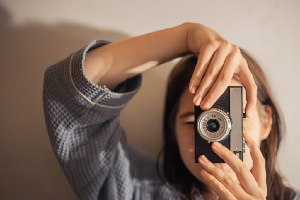 Pessoa fotografando com câmera analógica, representando o uso do filme em 2026